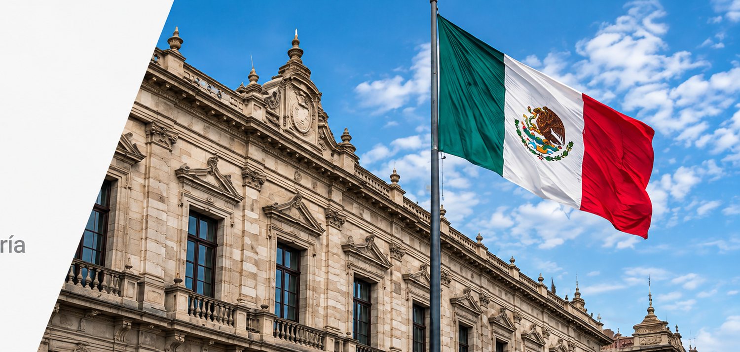 La fachada de un edificio público de cantera con la bandera de México ondeando en primer plano.
